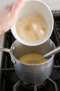 adding gelatin to a saucepan with pineapple juice