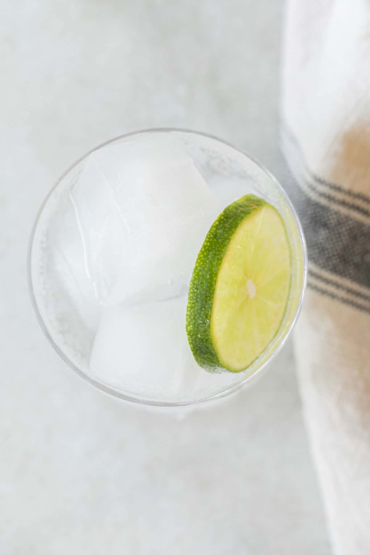 glass of ice and clear liquid with lime slice