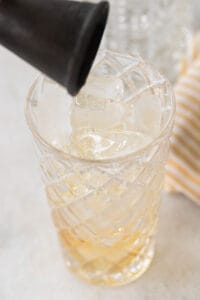 pouring whiskey into a highball glass