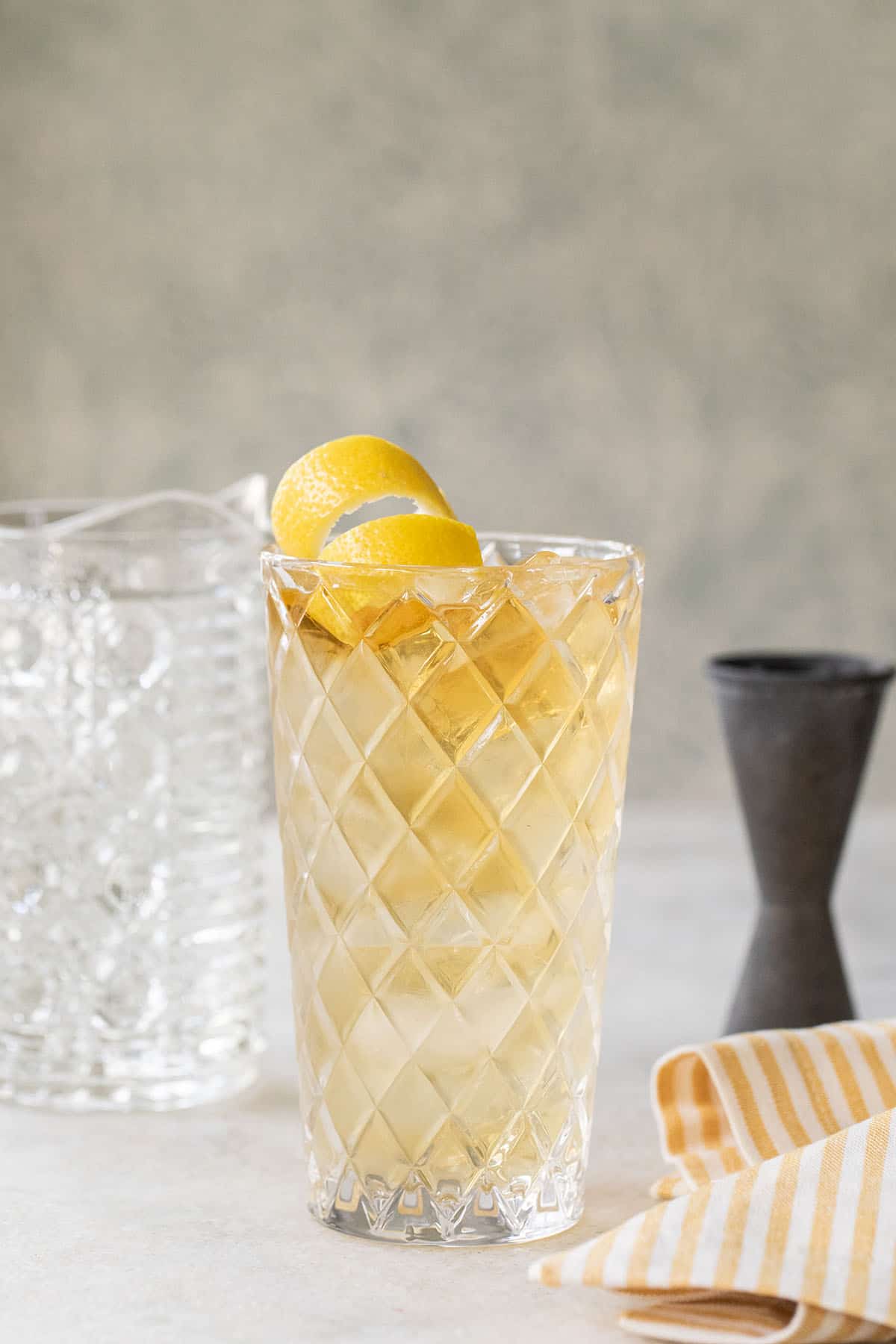 Whiskey highball in a tall glass with a lemon twist. 