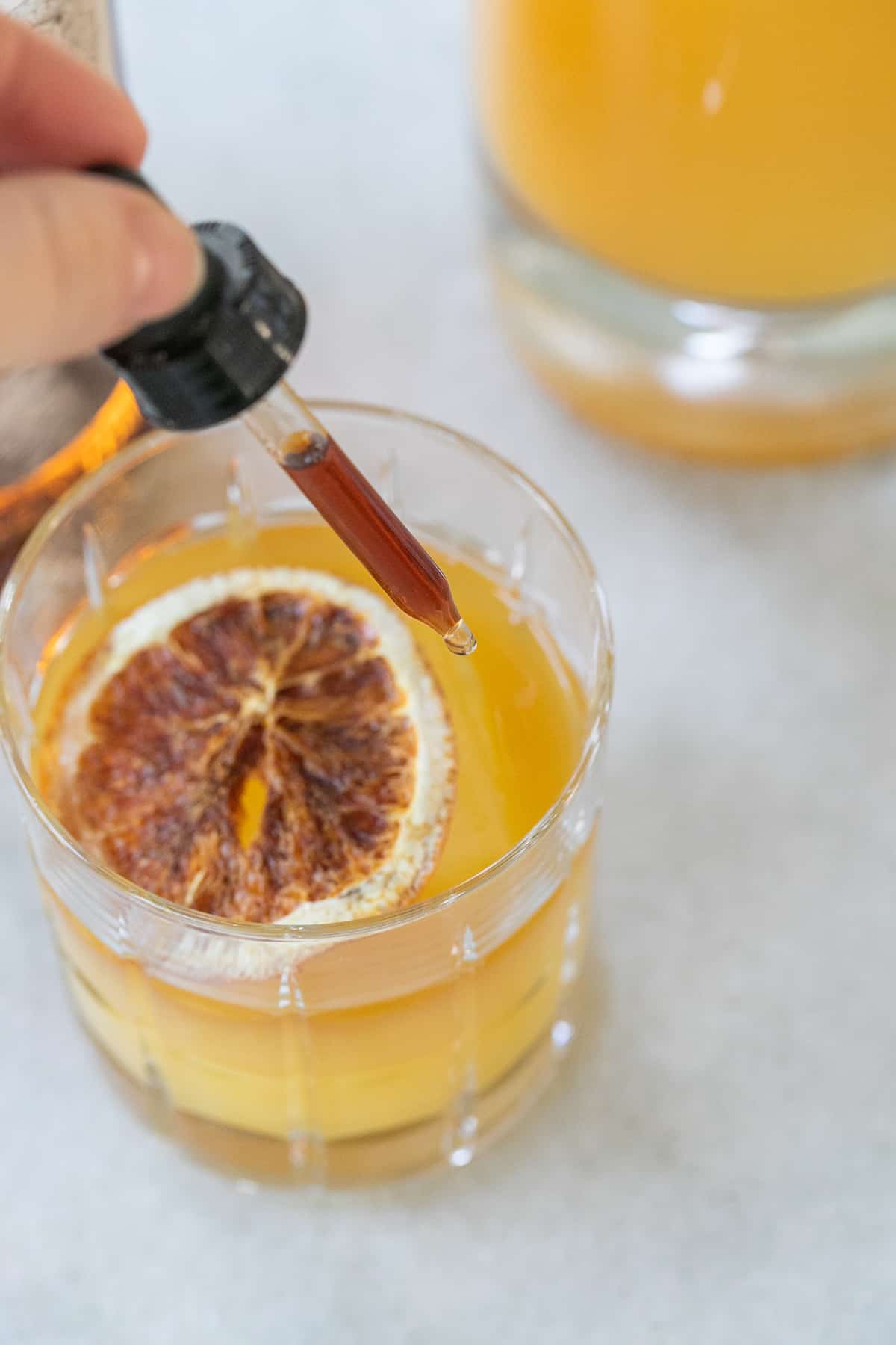 adding bitters to orange juice cocktail