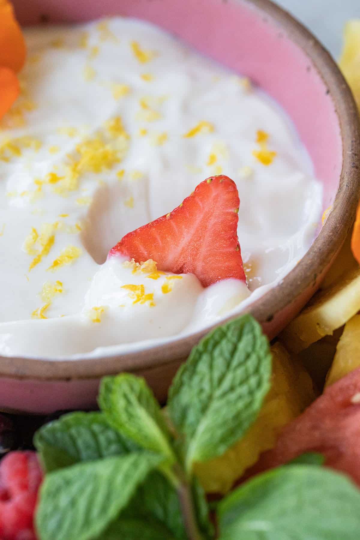 strawberry being dipped in a yogurt dip