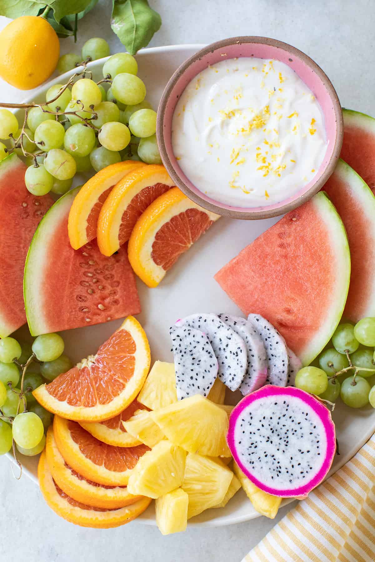 Watermelon, sliced oranges and fruit dip on a tray.