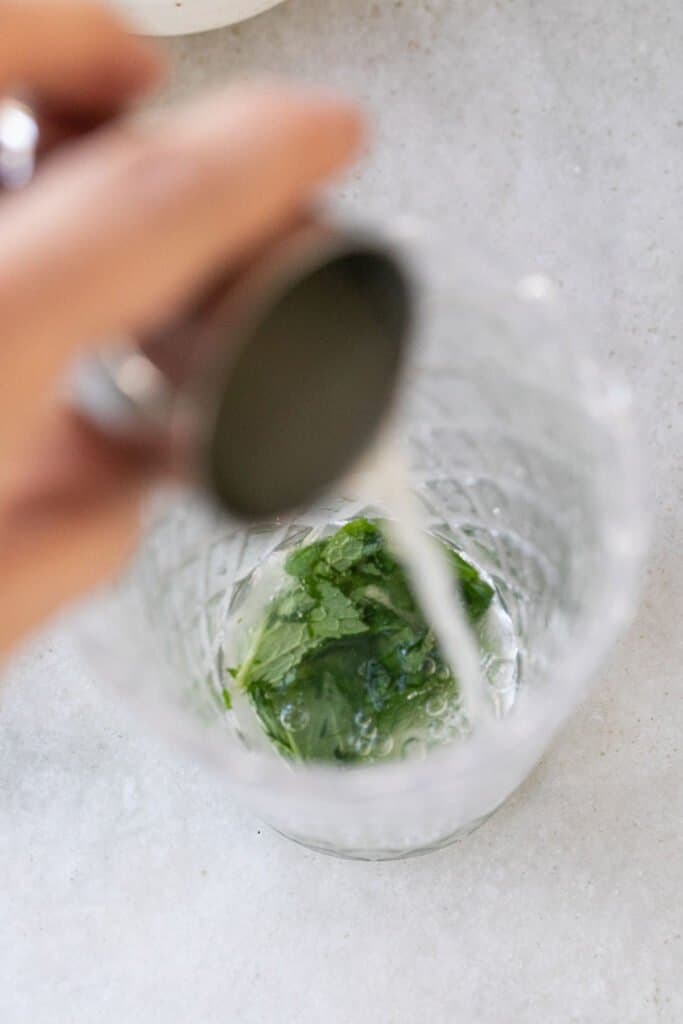 adding lime to juice to a highball glass