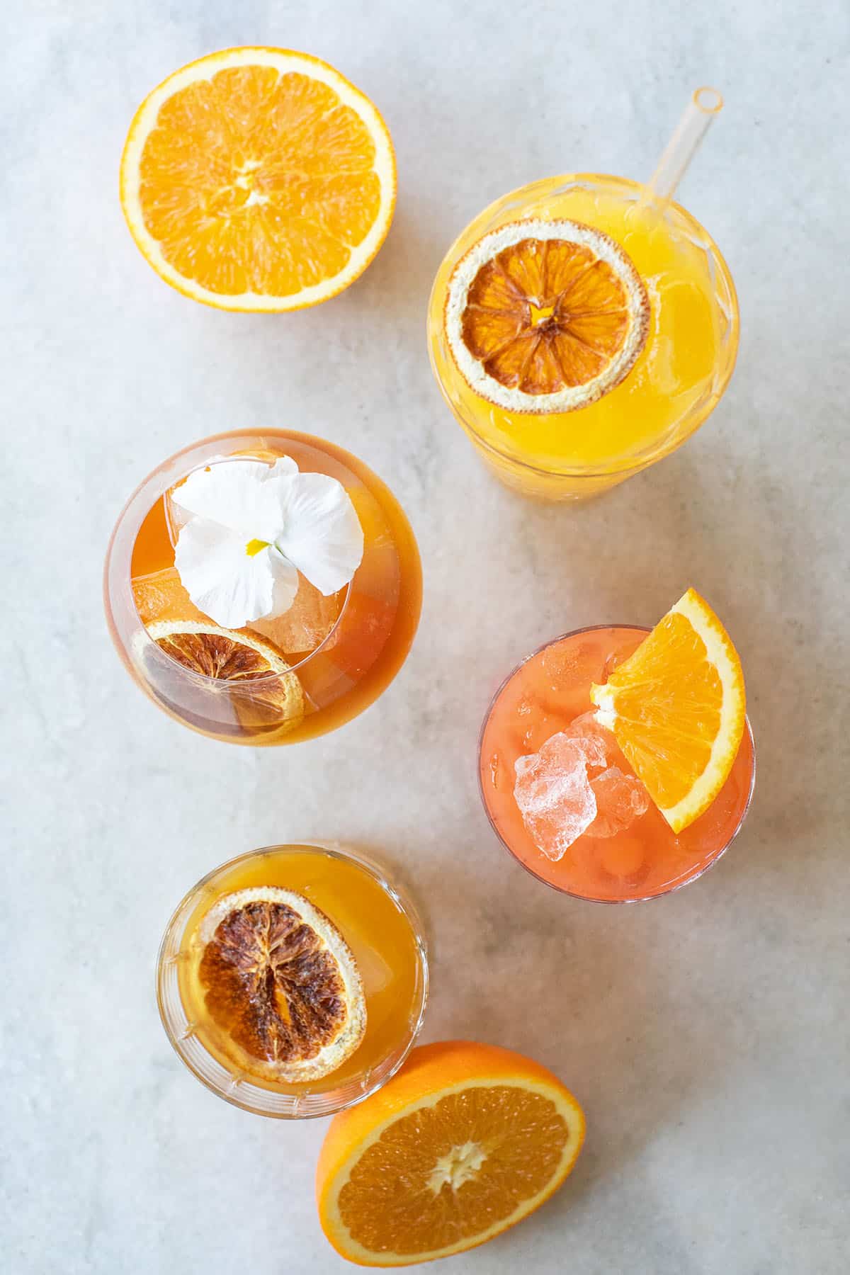 Orange juice cocktails with orange wedges on a white countertop. 