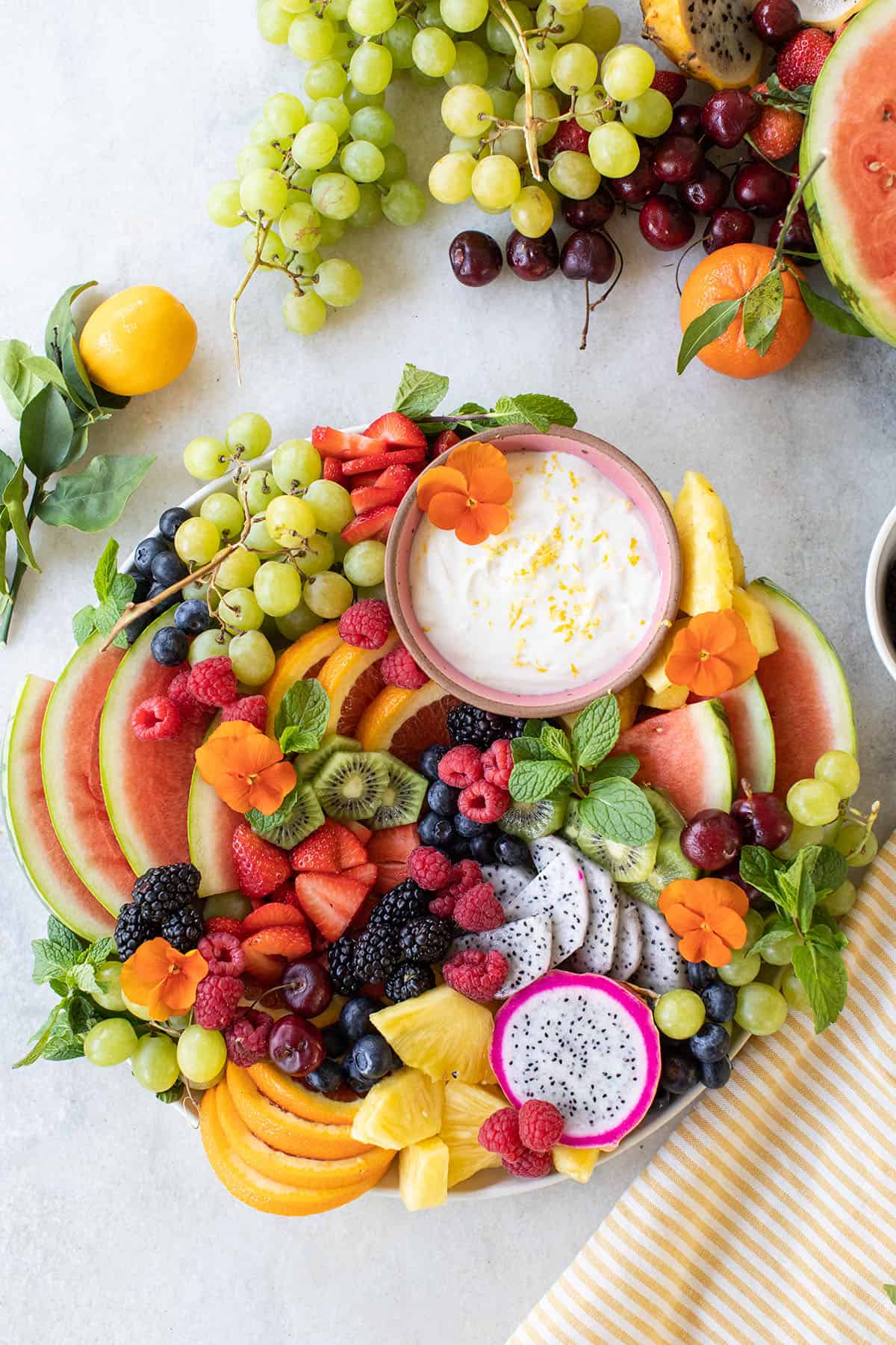 A beautiful fruit platter with watermelon, fresh mint, fruit dip, grapes, and colorful fruit.