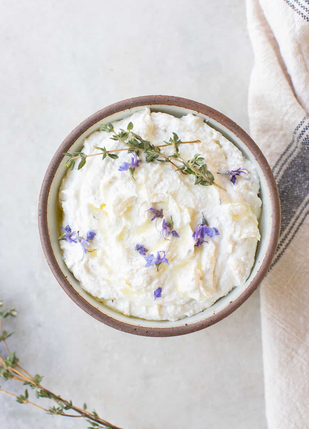 Whipped goat cheese dip with thyme and edible flowers over the top.