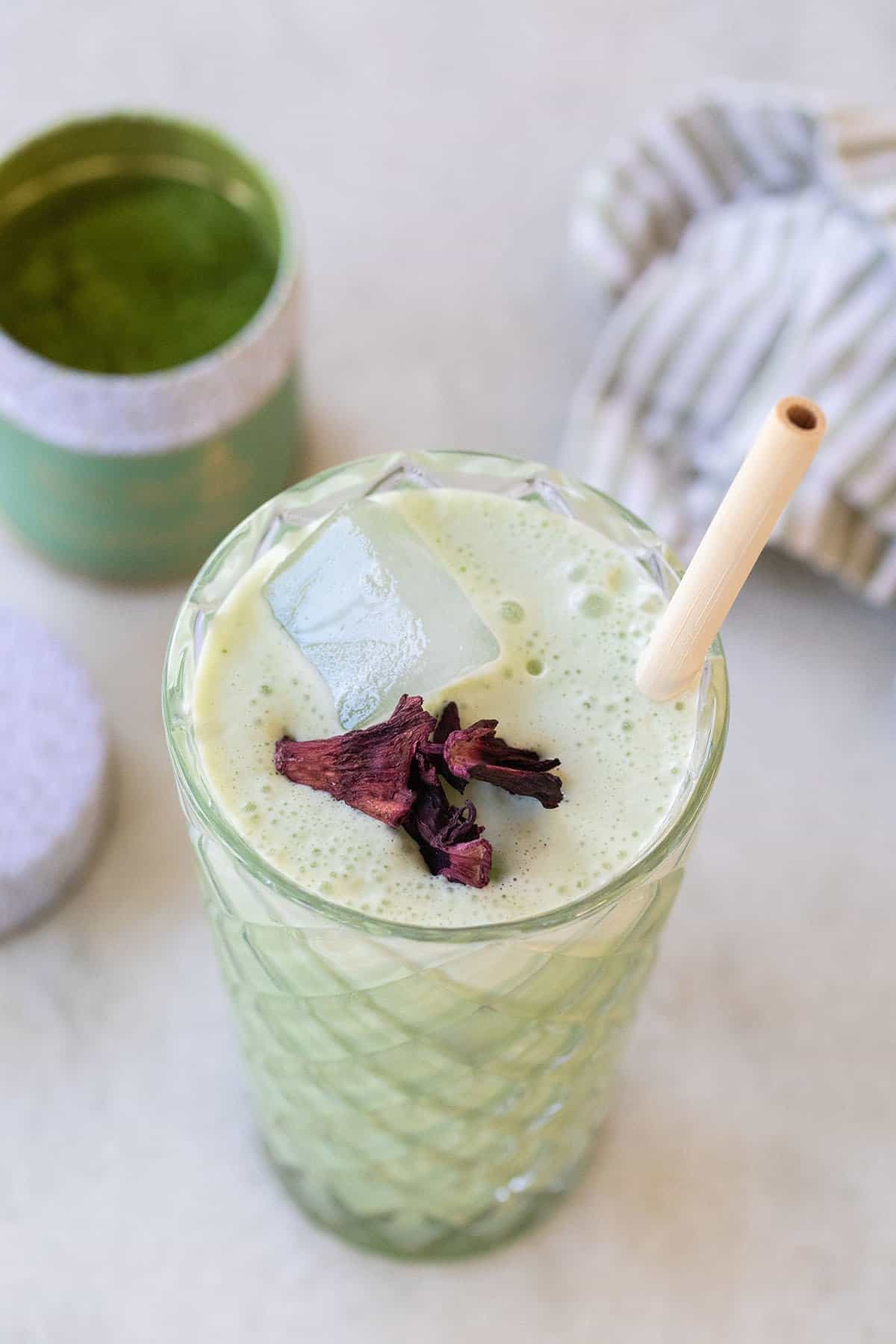 iced matcha latte in a tall glass with a bamboo straw