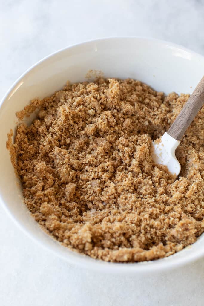 Mixing graham crackers in a bowl with butter.