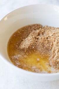 Graham cracker crumbs, butter and sugar in a bowl.