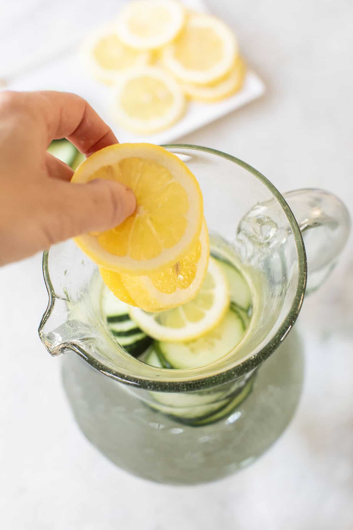 adding sliced lemons into water 