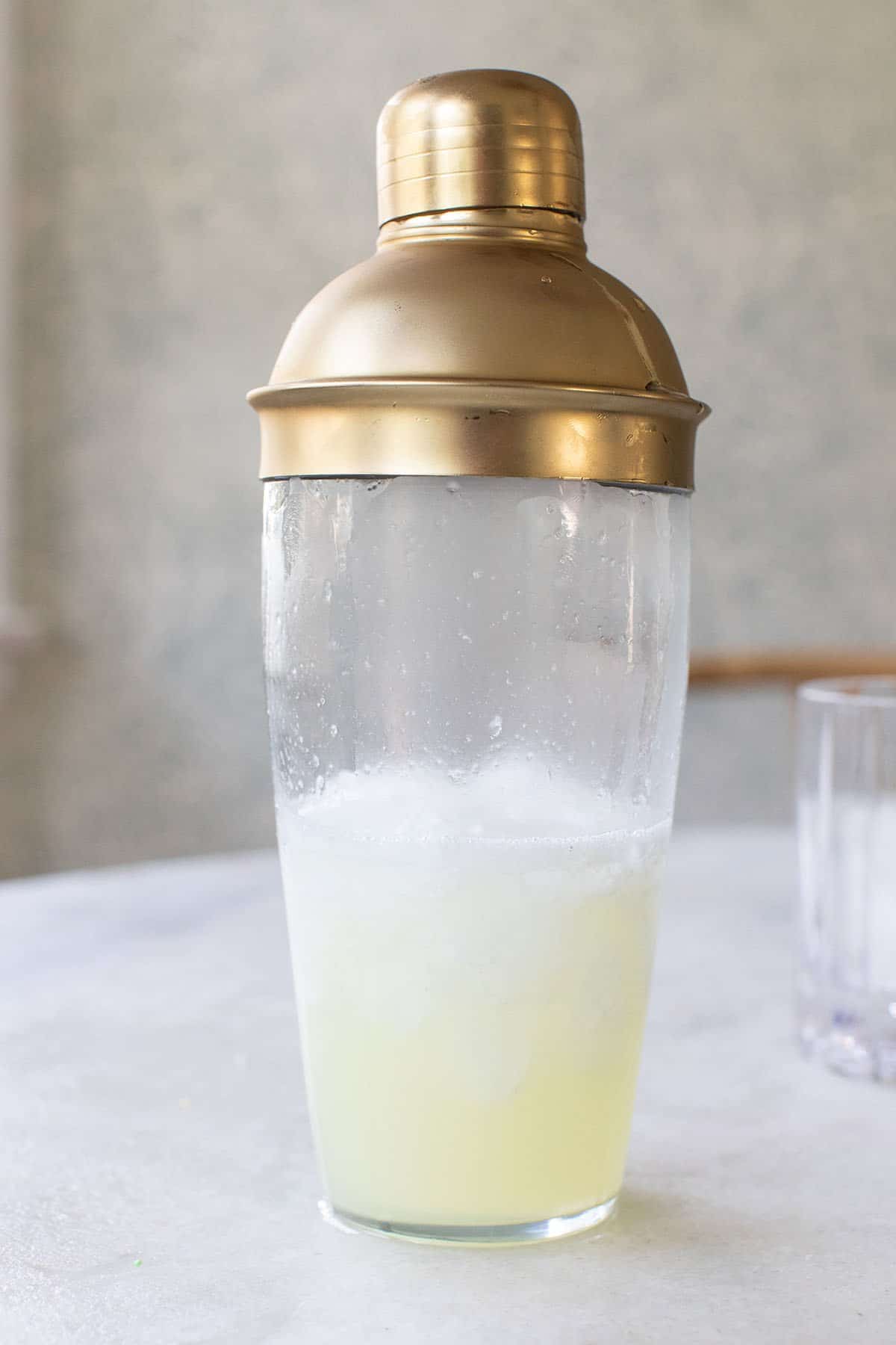 cocktail shaker filled with lemon juice, vodka, egg white and simple syrup