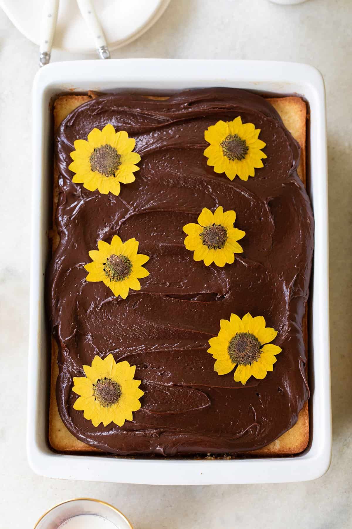 cake with chocolate frosting and edible dried flowers in a sheet pan