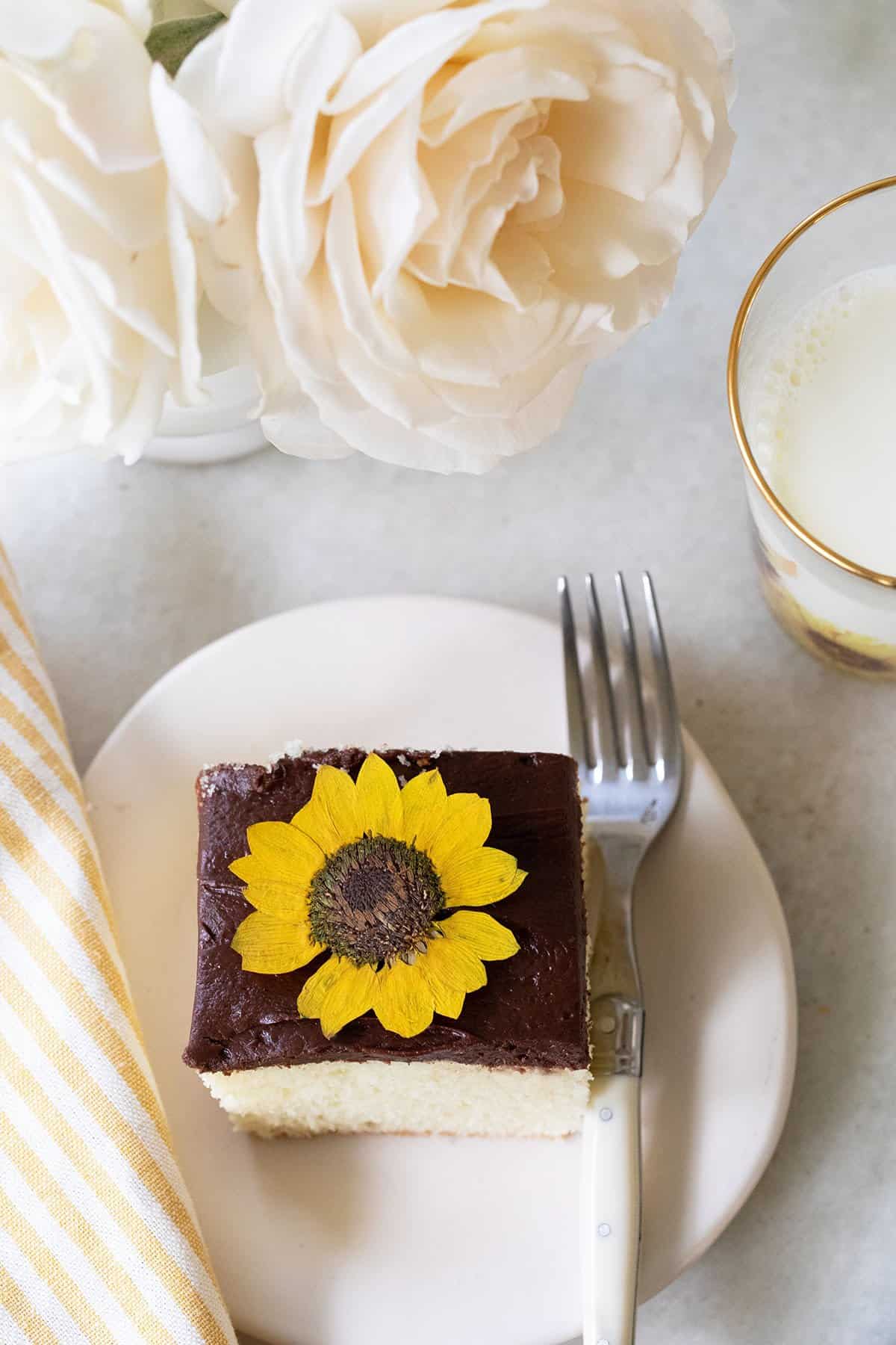 pretty slice of cake with frosting and en edible flower