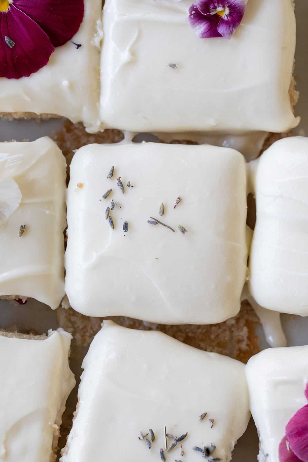 lavender cake with cream cheese frosting cut into squares