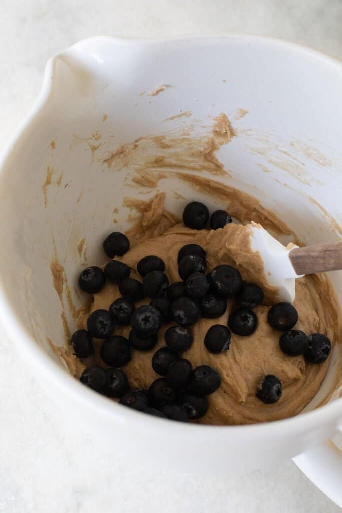 folding in blueberries into blueberry donut batter.