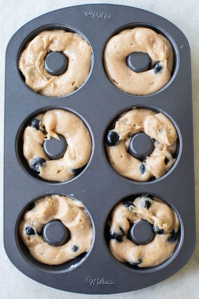 Donut batter in a pan to make baked blueberry donuts.