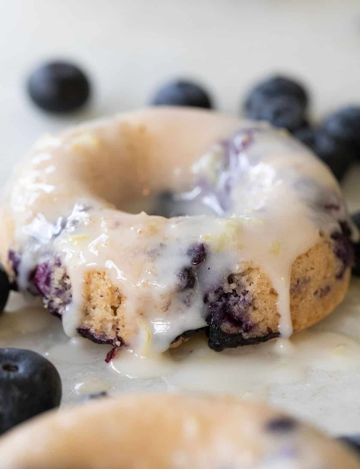 Glazed blueberry donut with juicy blueberries and dripping vanilla glaze.