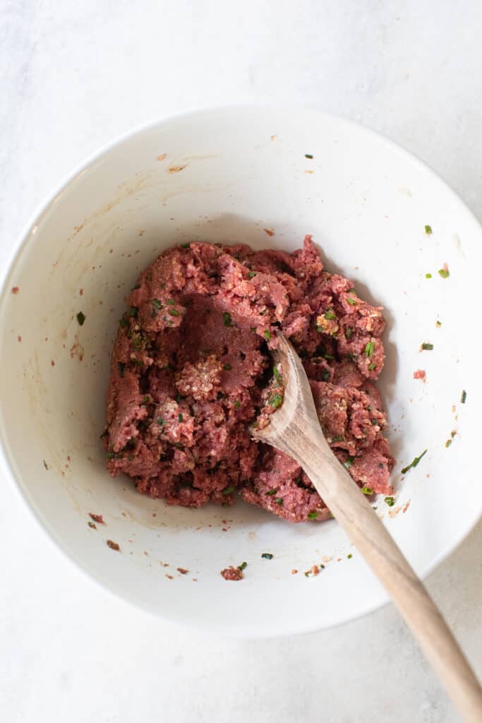 Mixing meat and spices to make appetizer meatballs.