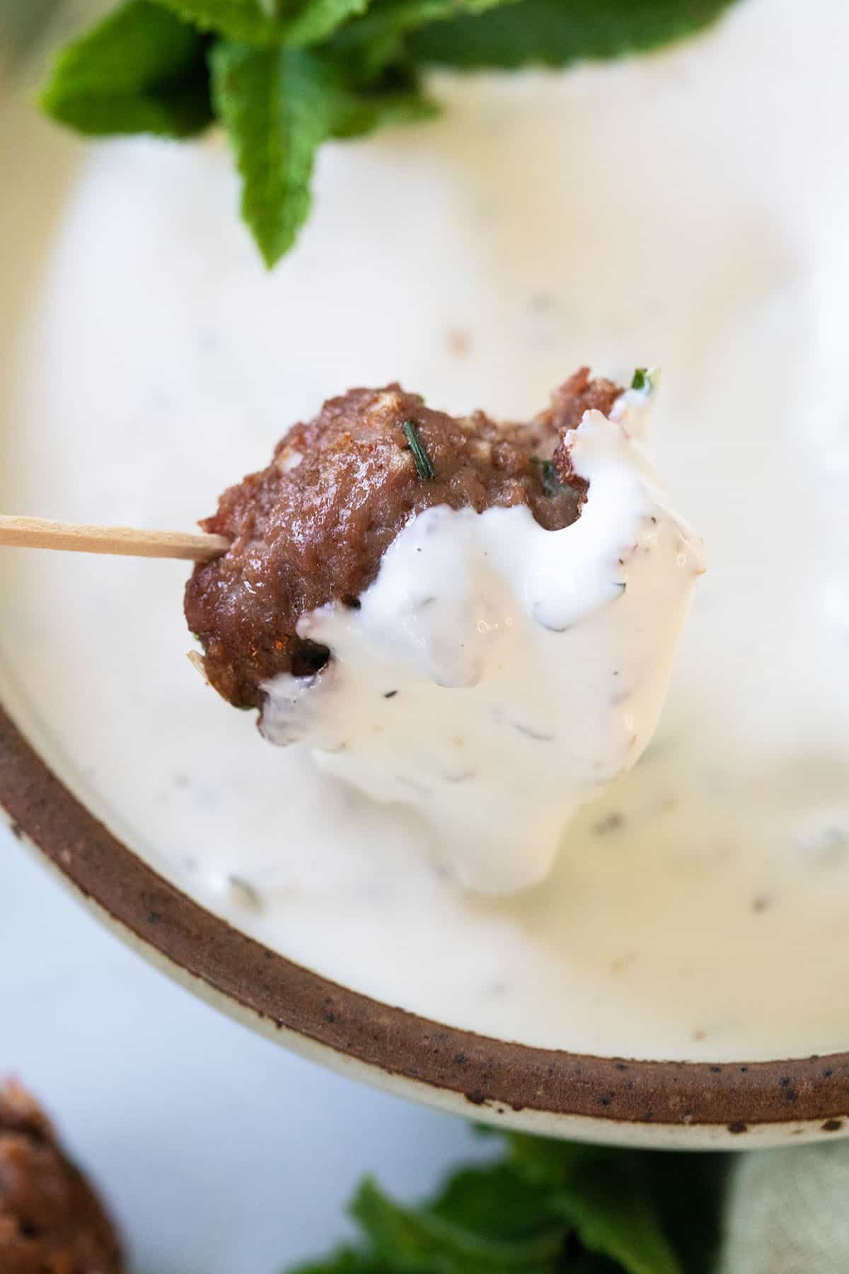 dipping a cocktail meatball into garlic sauce