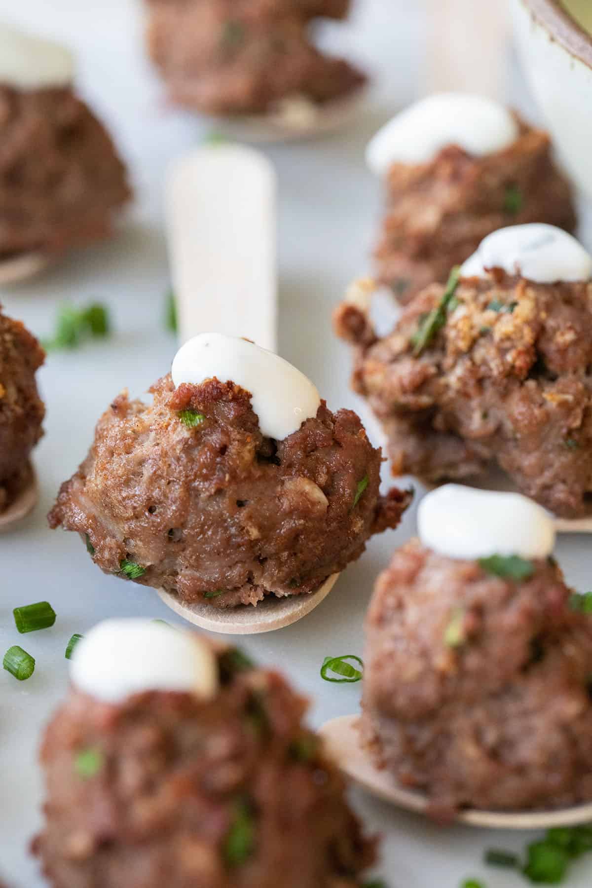 mini meatballs on small wooden spoons with sauce