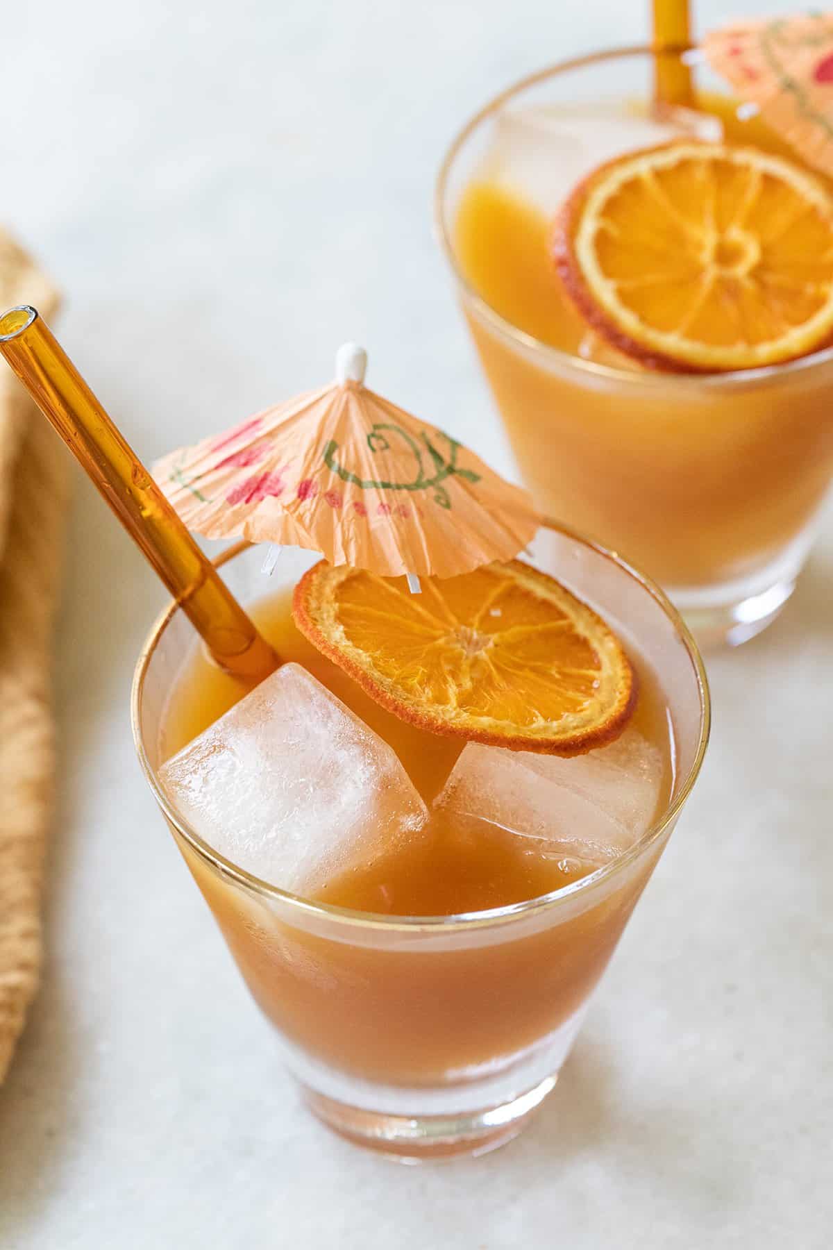 Orange cocktail recipe with orange slice and umbrella. 