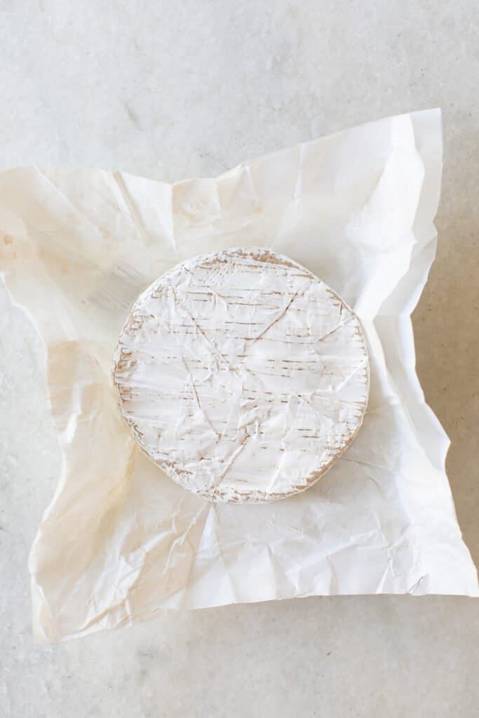 A Brie cheese wheel on parchment paper.