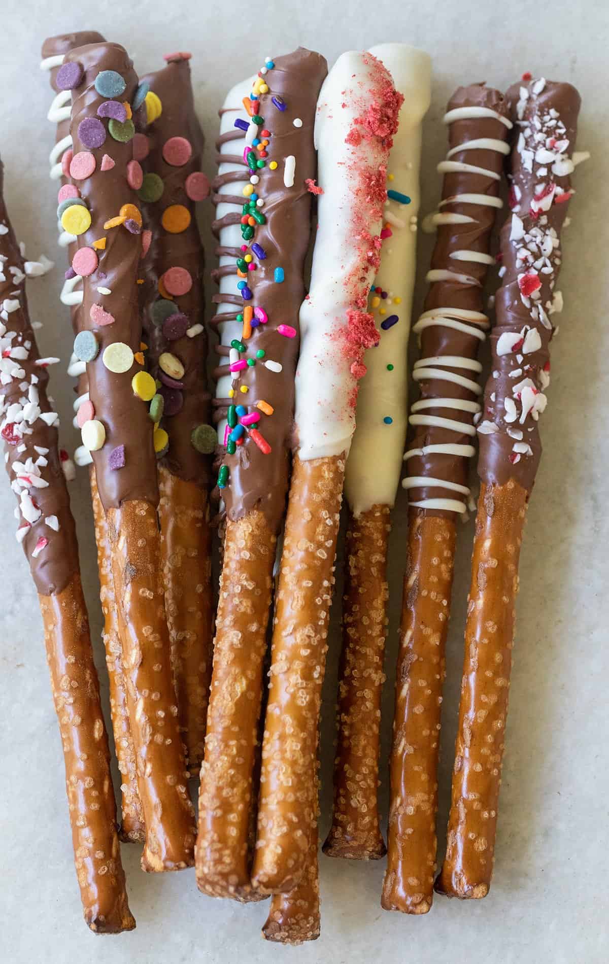 Decorated chocolate covered pretzel rods with sprinkles.