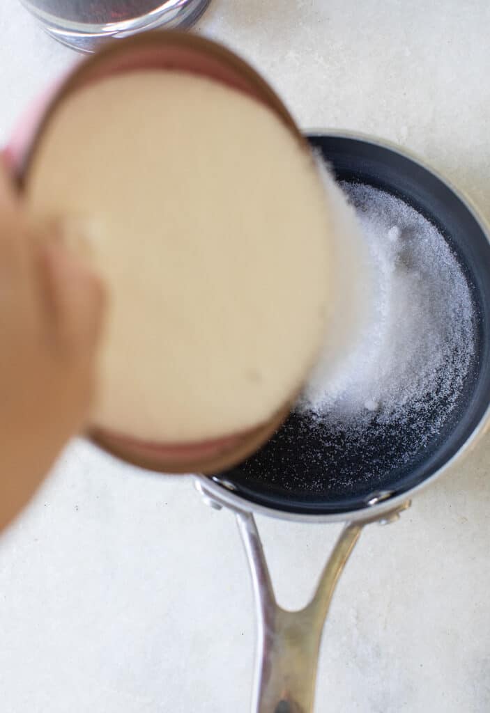 Pouring sugar into a small pot.