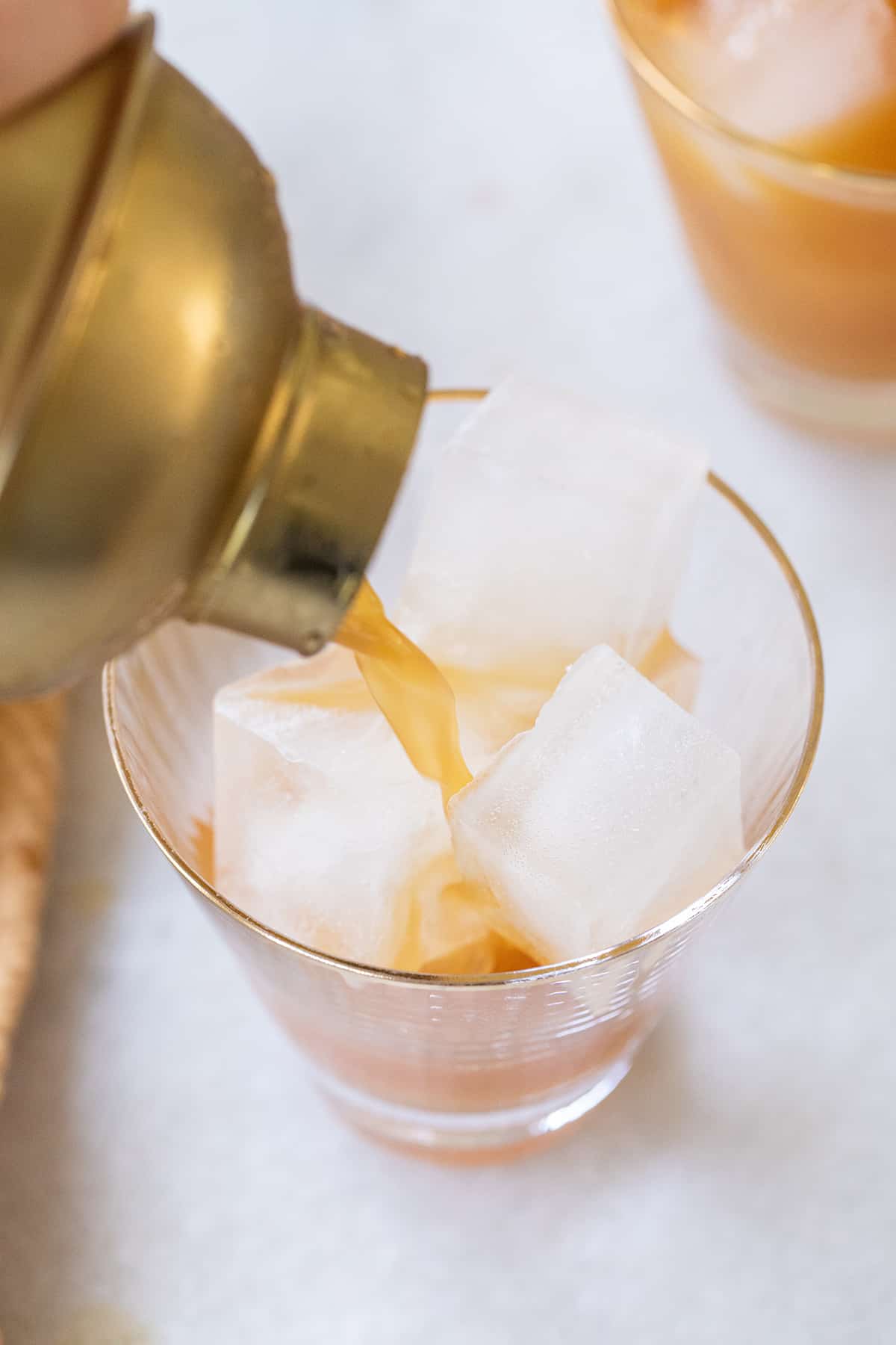 Pouring a rum cocktail into a glass filled with ice.