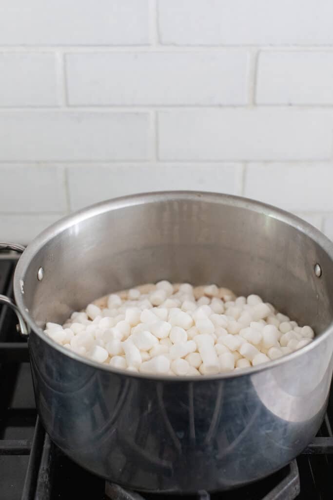Adding marshmallows into a large pot.