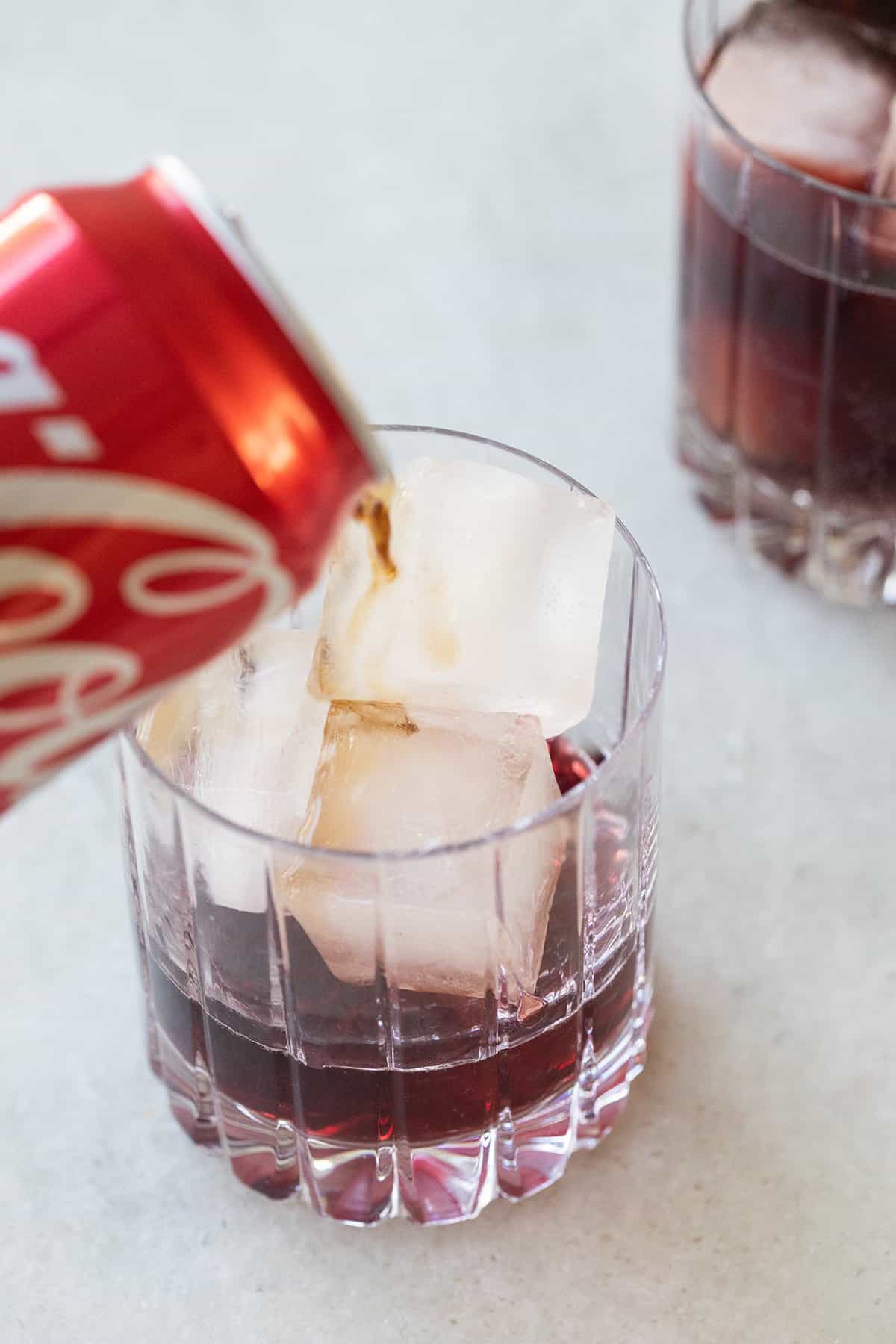 Pouring coke into a glass with red wine to make a Kalimotxo recipe. 