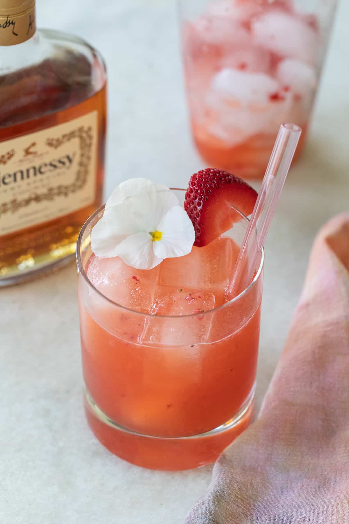 Strawberry Hennessy drink with a white flower and straw.