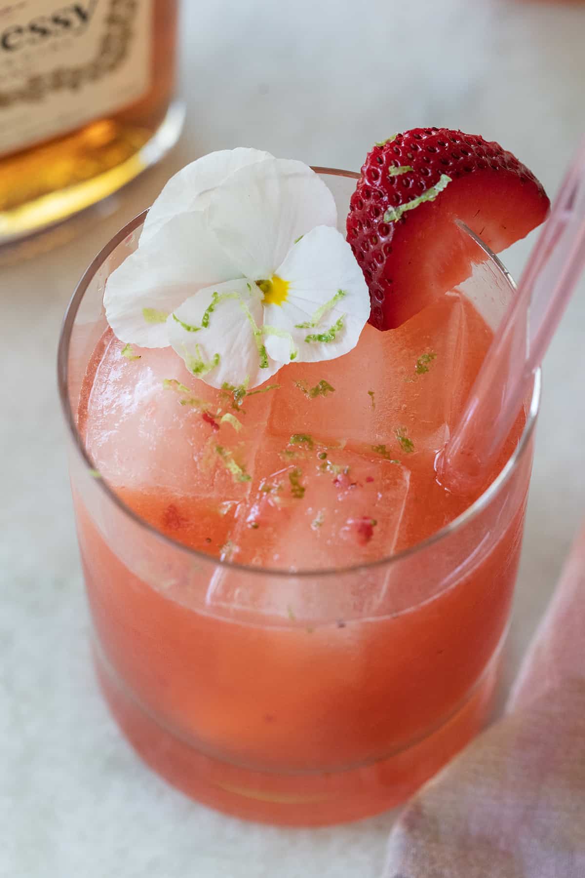edible flower and lime zest on a strawberry cocktail