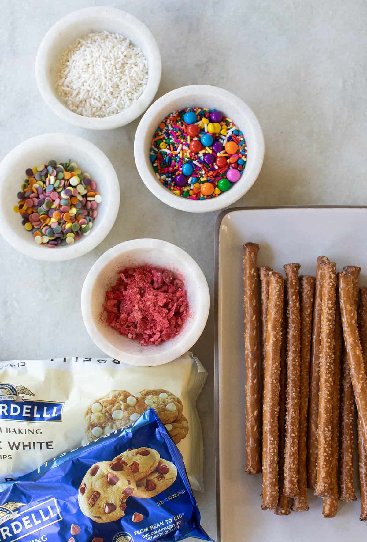 pretzel rods, sprinkles and bags of white chocolate chips and milk chocolate chips