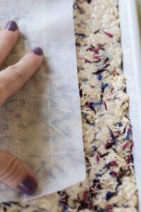 pressing parchment paper down on rice krispie treat to get an even layer
