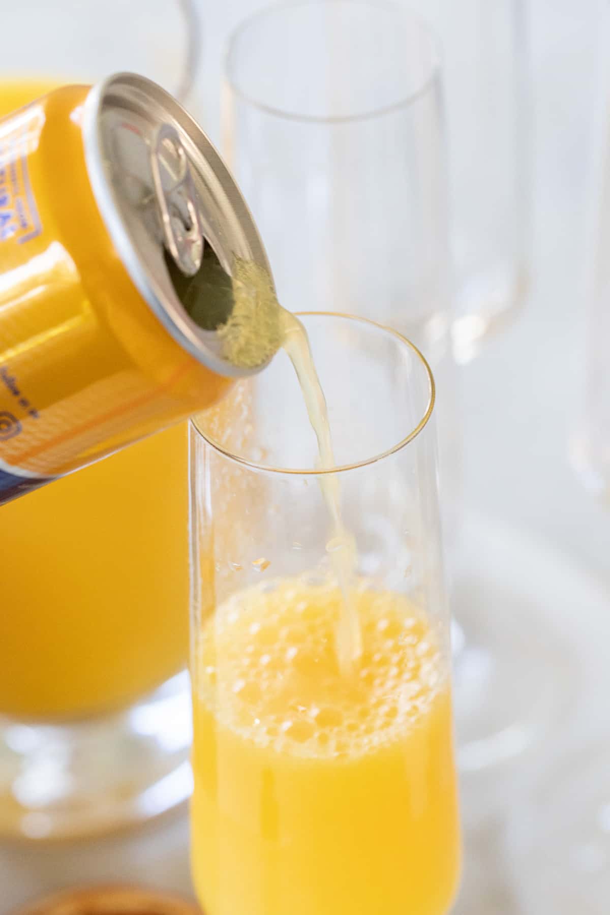 pouring an orange beverage into a Champagne flute