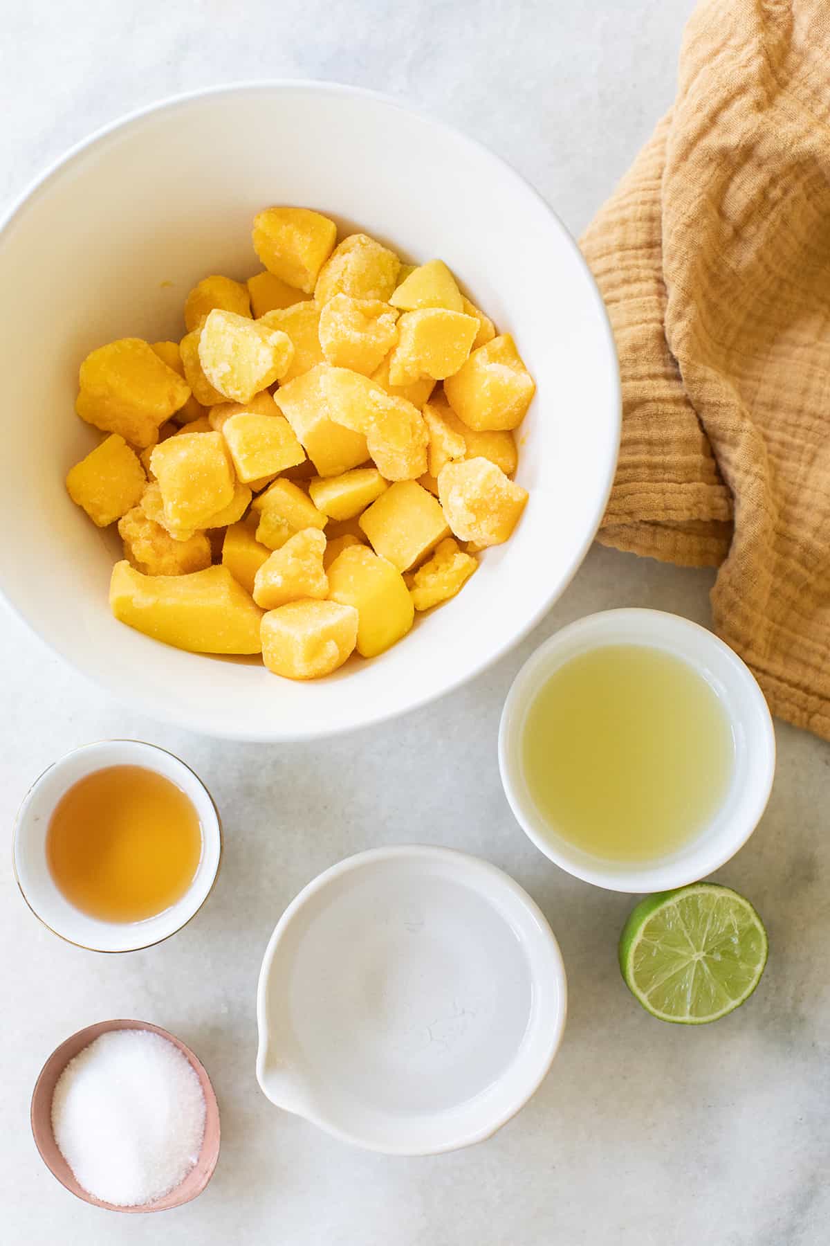 Frozen mango, lime juice, tequila, sugar, agave to make frozen mango margaritas.