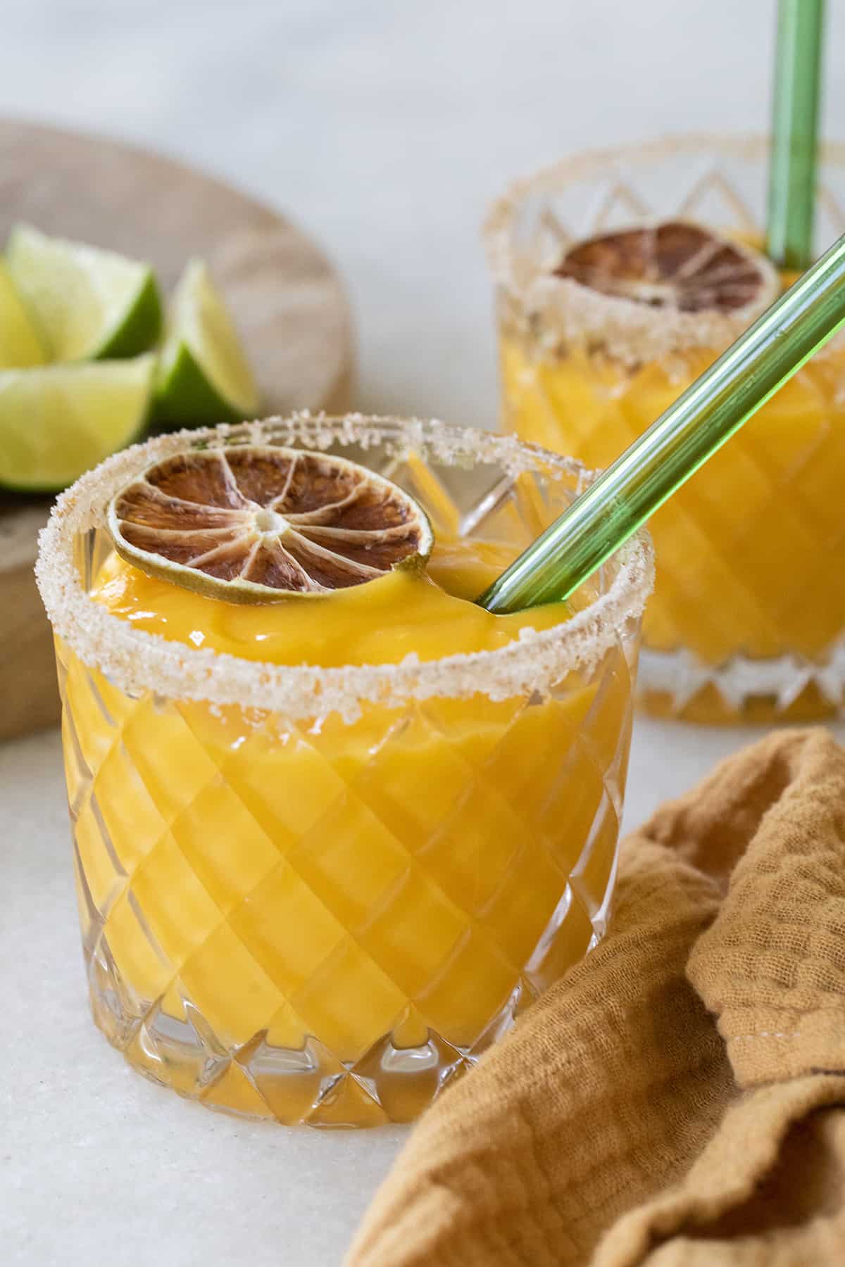 Frozen mango margarita with a green straw.