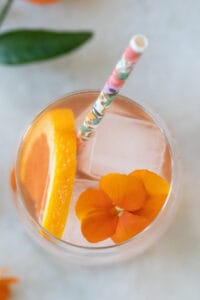 edible flowers and orange slice in a cocktail