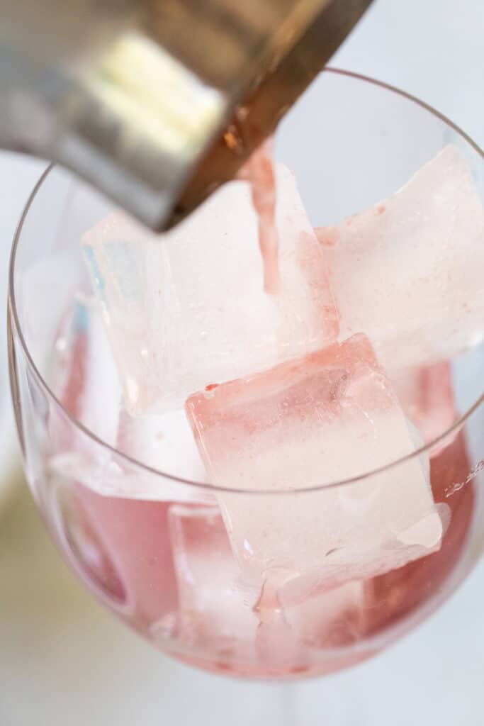 pouring a cocktail into a large wine glass