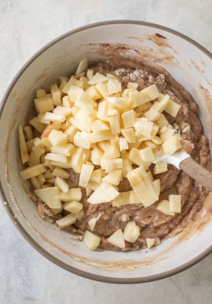 Folding chopped apples into apple cake batter. 