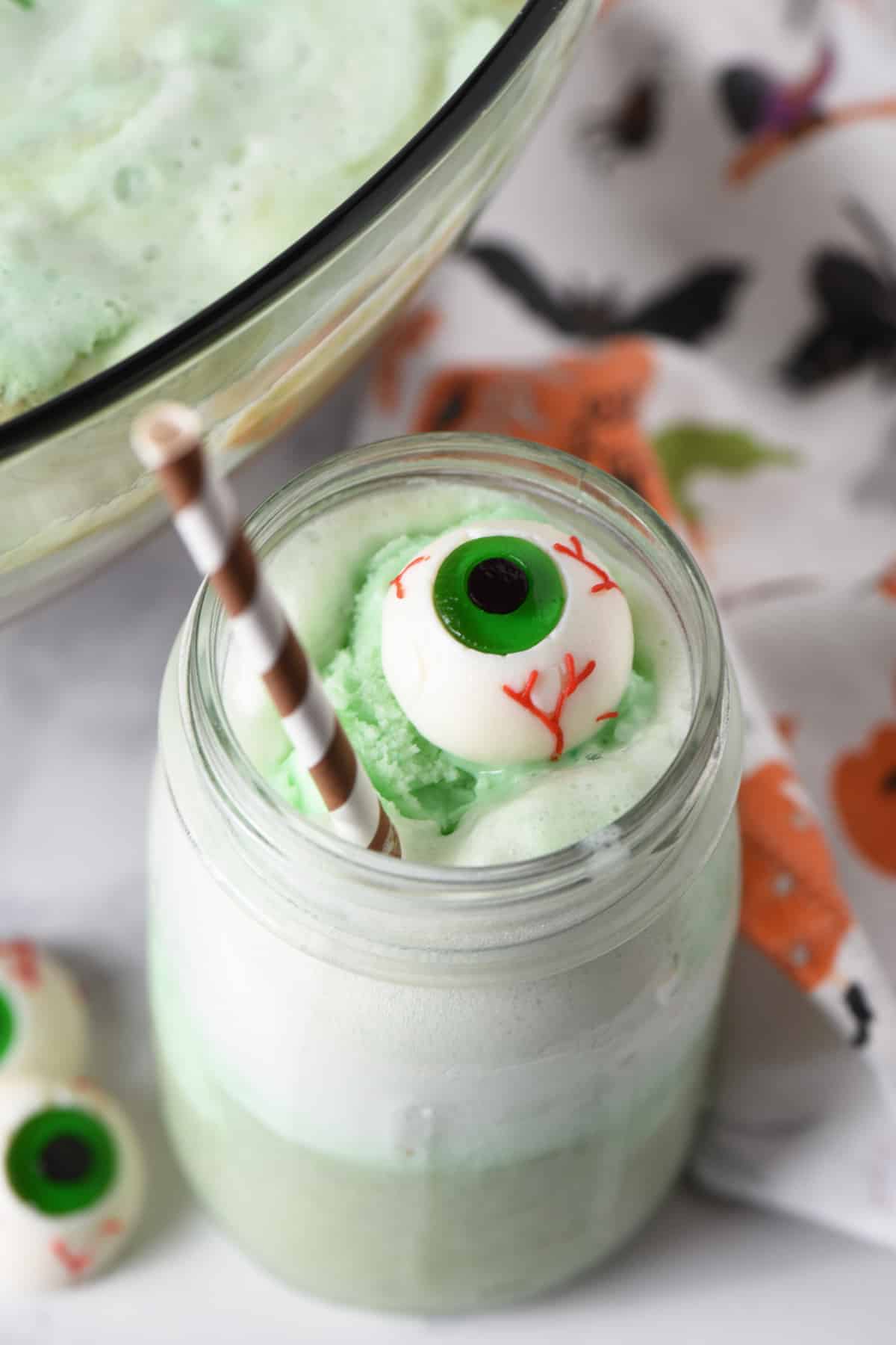 Green Halloween drink with candy eyeball and straw.