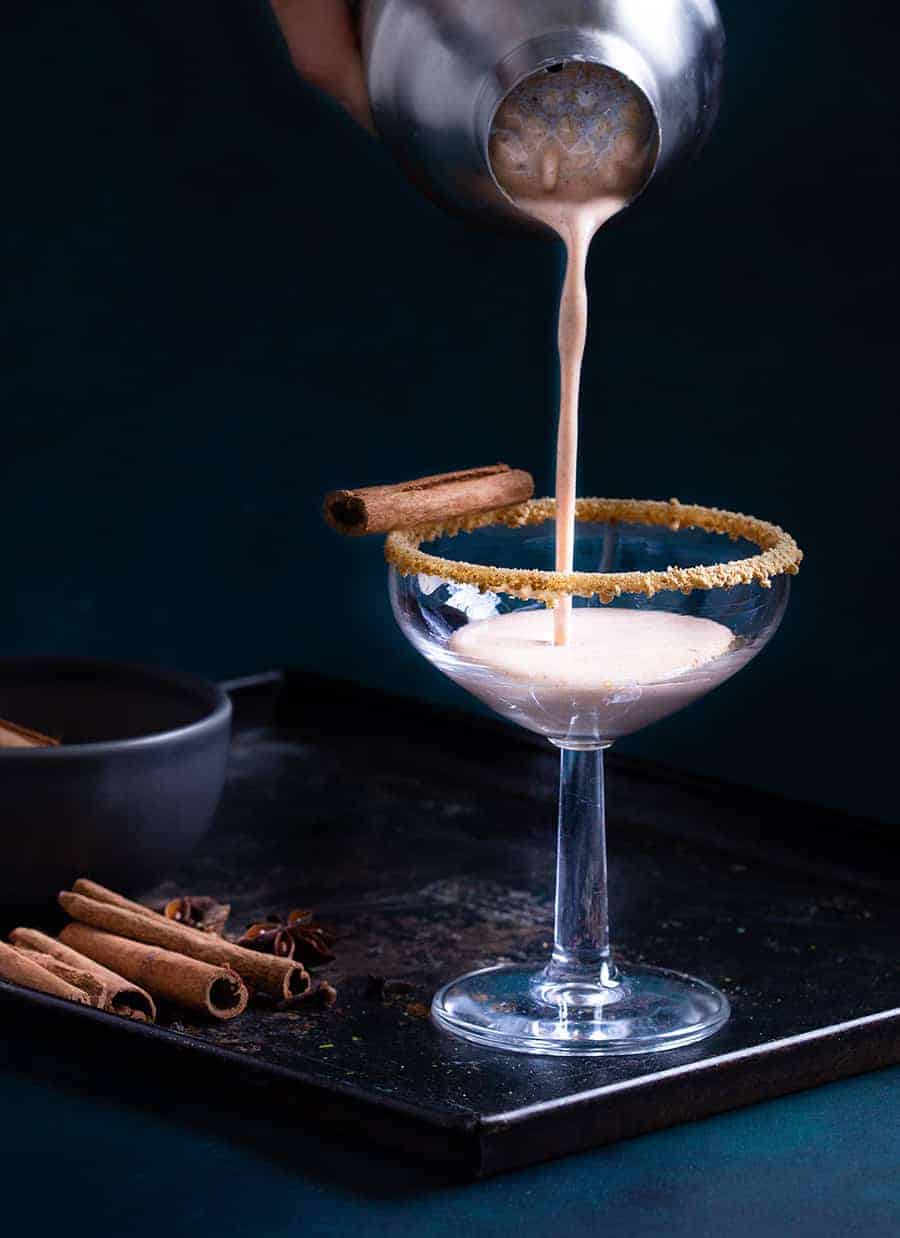 Pouring a non-alcoholic pumpkin martini into a glass.