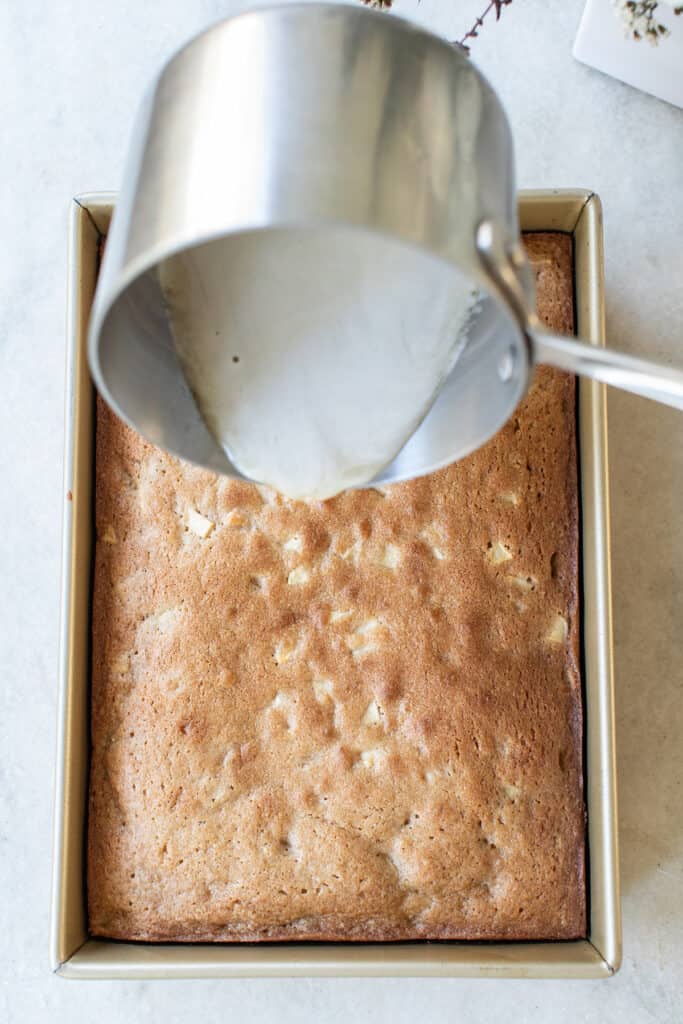 Pouring glaze over the top of an apple cake.