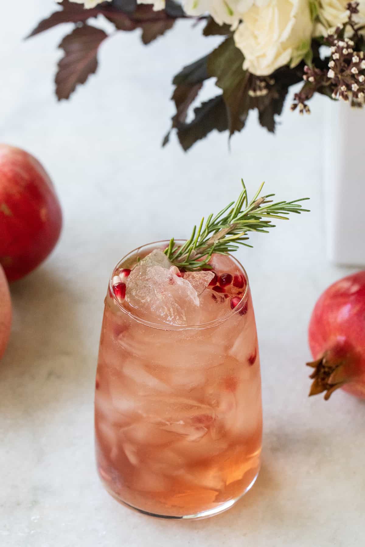 red cocktail with pomegranates and rosemary in a glass