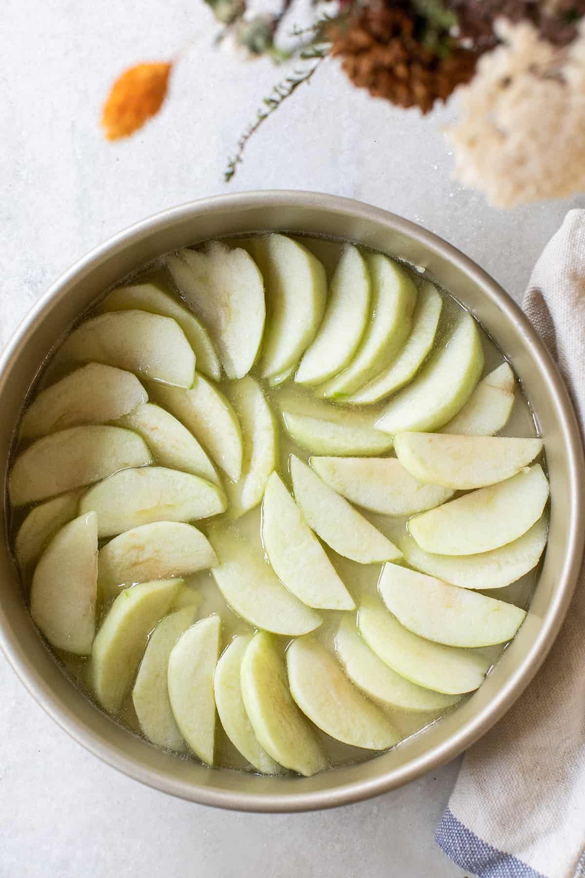 Apples arranged in a round cake tin.