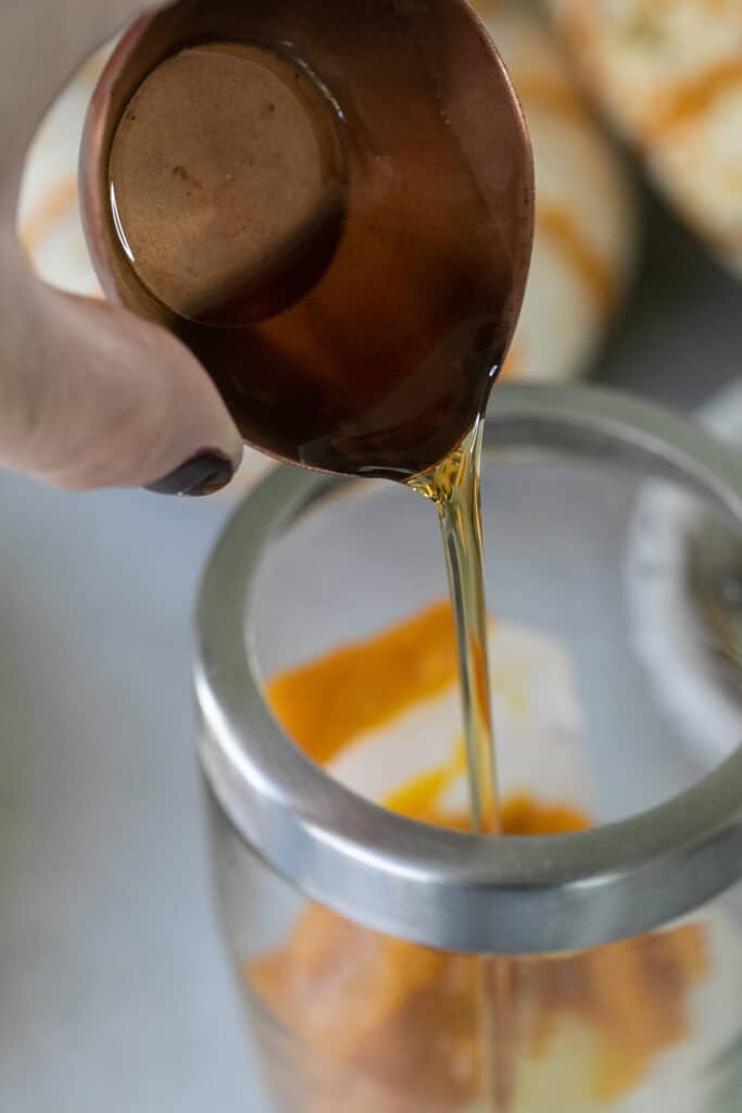 Pouring maple syrup into a cocktail shaker.