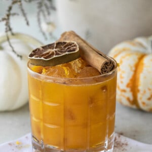 Pumpkin spice margarita in a glass with a cinnamon stick and lime wheel.