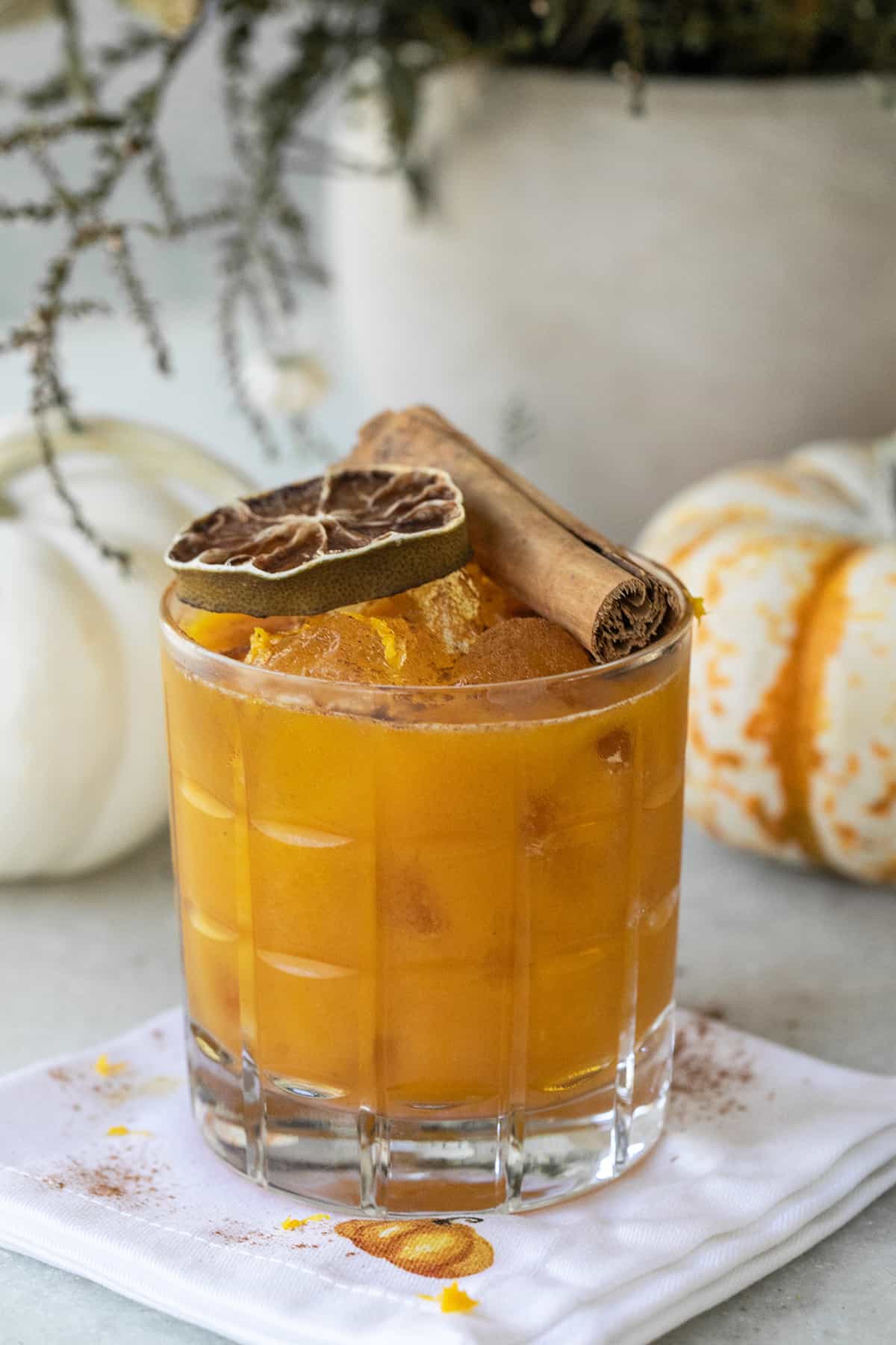 Pumpkin spice margarita in a glass with a cinnamon stick and lime wheel.